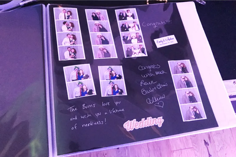 Close up of a handcrafted photo booth guestbook with silver pen writing on black cardstock